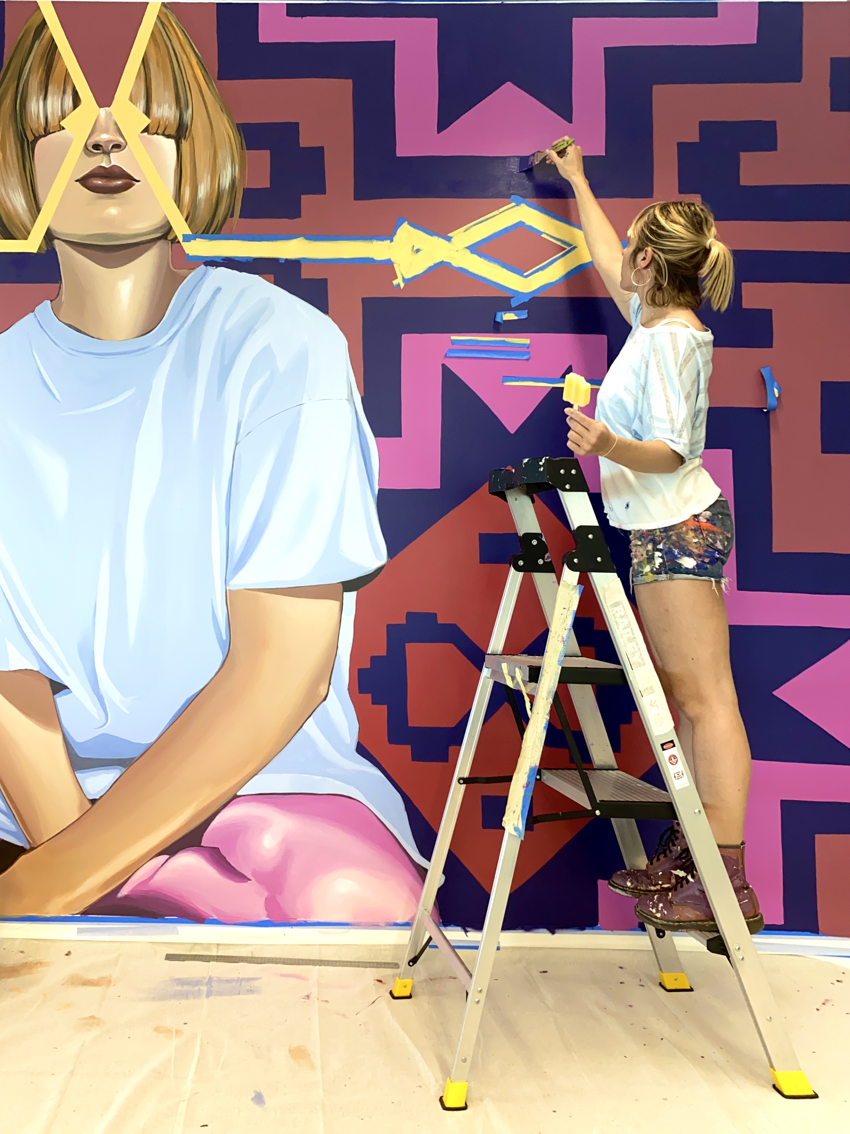 Image of artist Lucy Lucy painting a mural.
