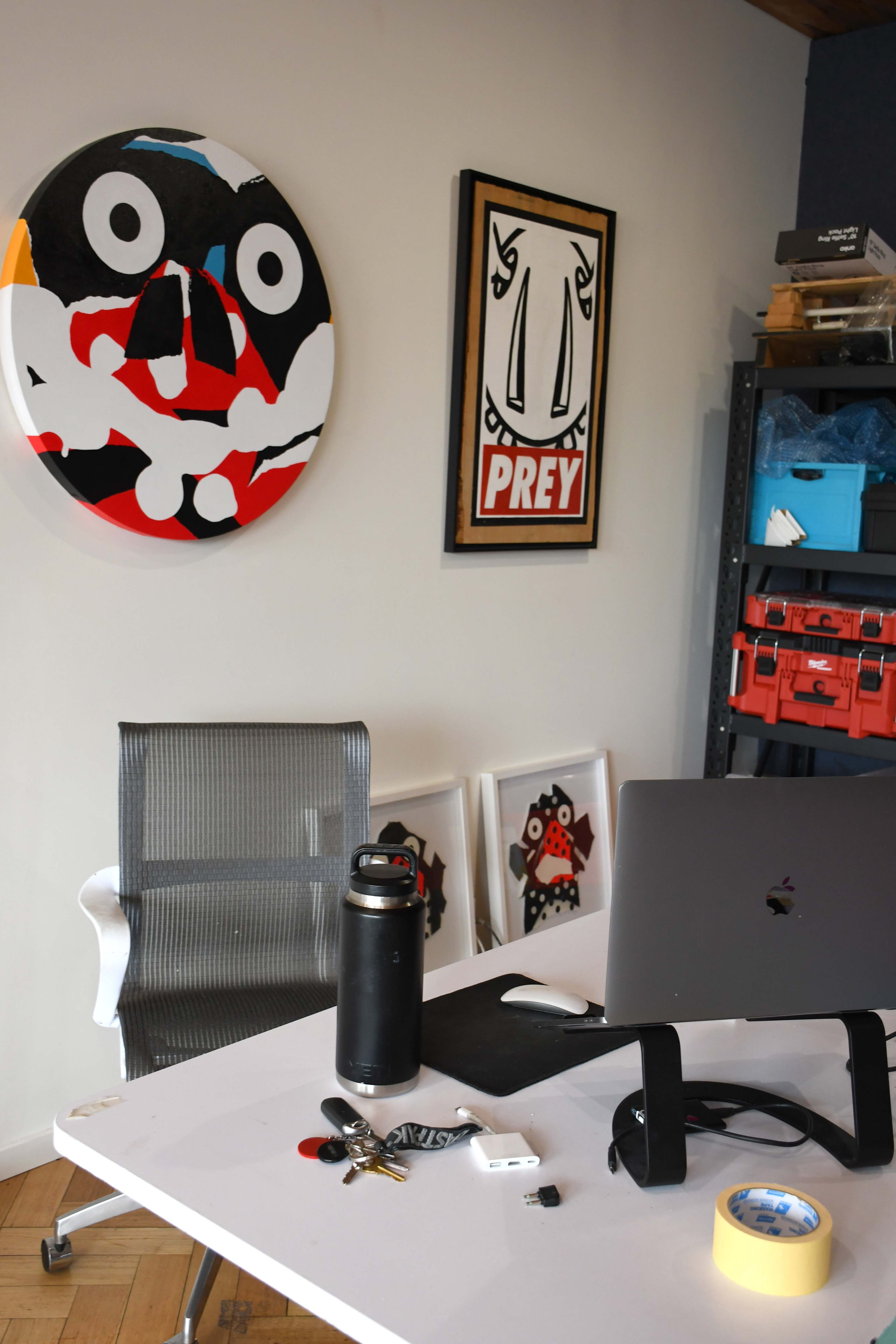 A photo of Mysterious Al's Digital art workspace, including his painted works in the background and computer.